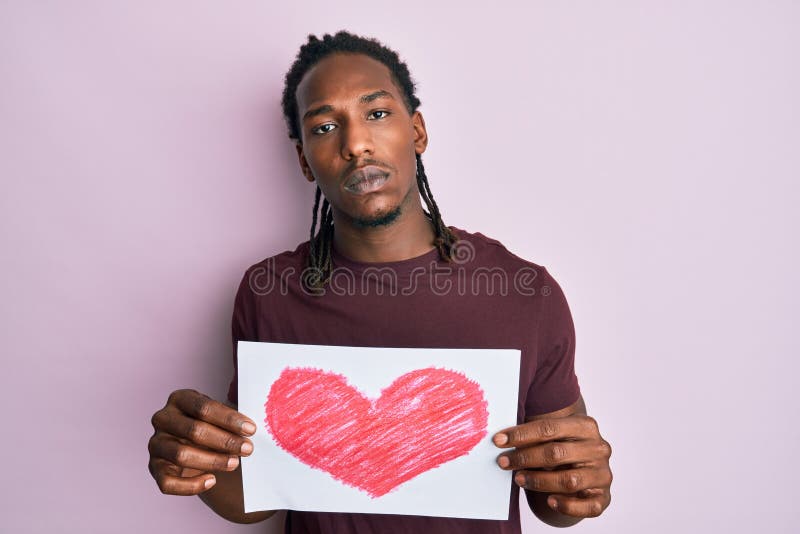 African american man with braids holding heart draw relaxed with serious expression on face