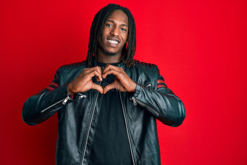 African american man with braids wearing black leather jacket smiling in love doing heart symbol shape with hands