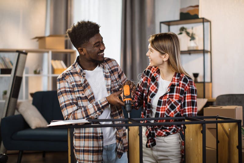 Happy multi ethnic couple with tools assembling furniture royalty free stock photo
