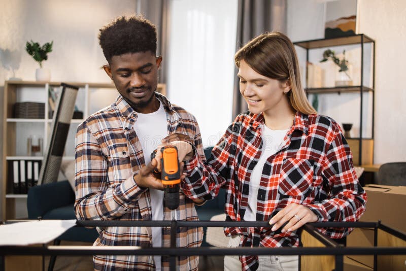Happy multi ethnic couple with tools assembling furniture royalty free stock images