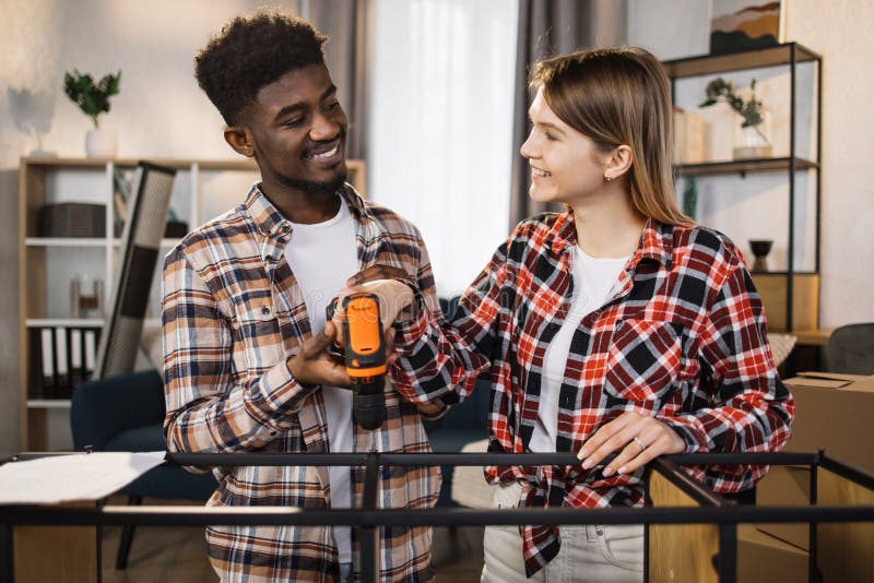 Happy multi ethnic couple with tools assembling furniture stock images
