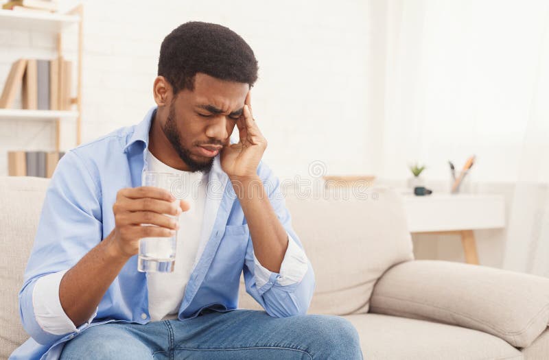 African-american man with headache taking pill at home stock image African-american man with headache taking pill at home stock image