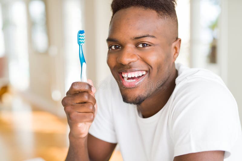 African American Man Holding Toothbrush with a Happy Face Standing and ...