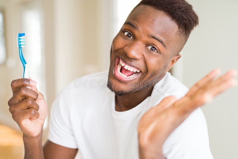 African American Man Holding Toothbrush Very Happy and Excited, Winner ...