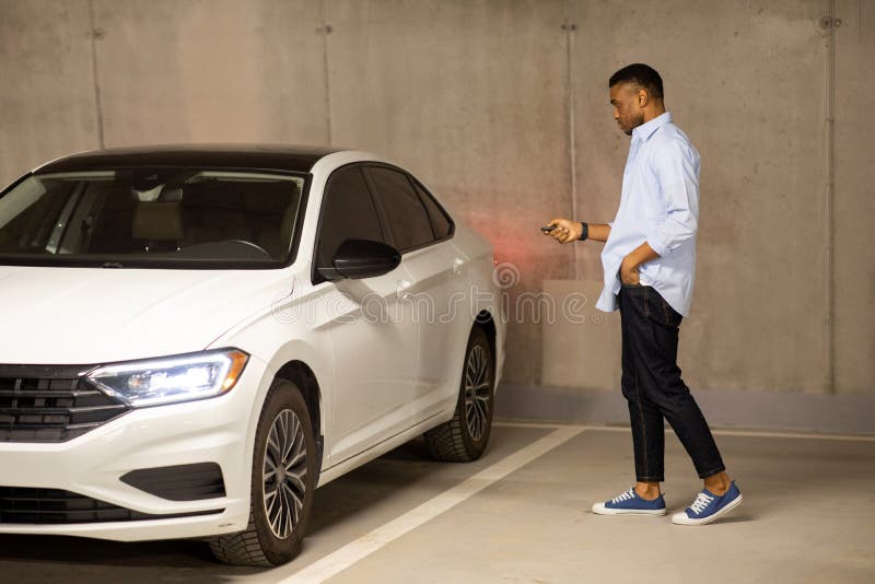 African American Man Opens His Car With Keys In An Underground Parking