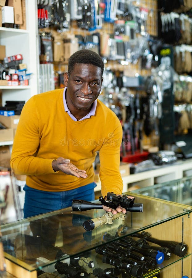 Salesman in arms shop presenting rifle telescope royalty free stock image