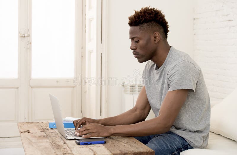 African american man sitting at home living room working with laptop computer and paperwork