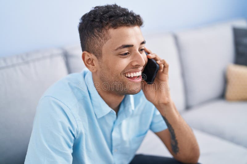 African american man talking on the smartphone sitting on sofa at home royalty free stock images