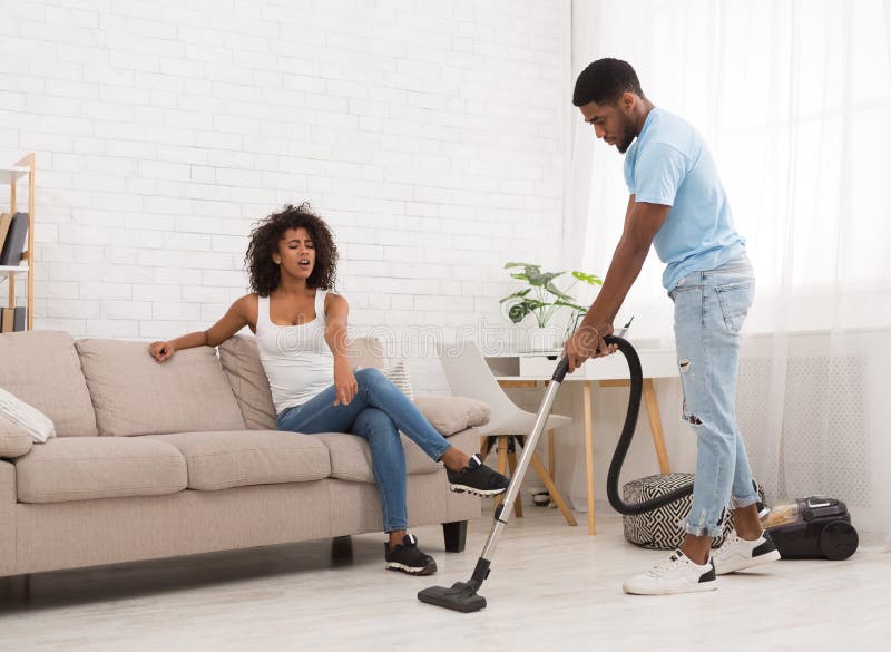 Black man cleaning house with wireless vacuum cleaner Stock Photo