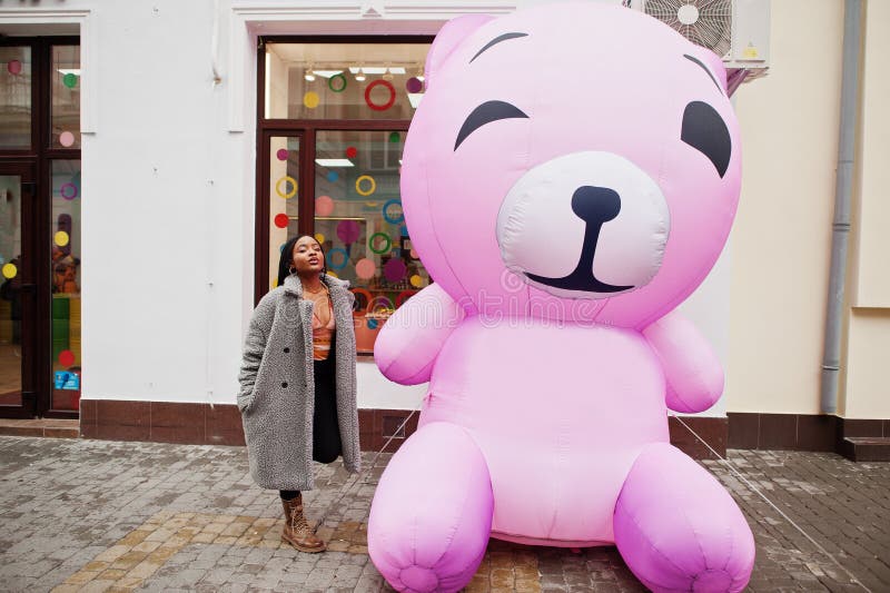 African american Millennium Lady nära uppblåsbar rosa teddy björn royaltyfria bilder