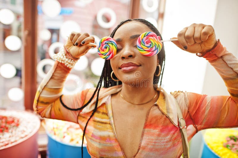 African american Millennium Lady på candy shop med lolipops täcker hennes ögon arkivfoto