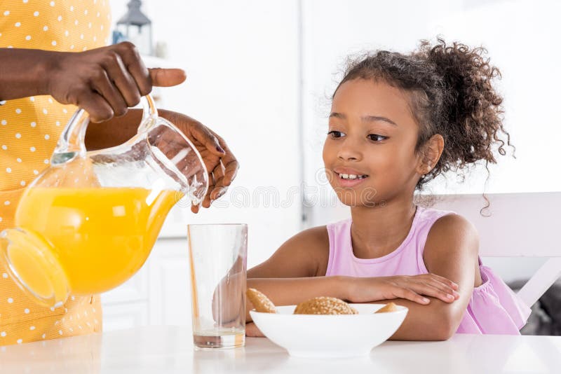 african american mother pouring orange juice for daughter stock images african american mother pouring orange juice for daughter stock images