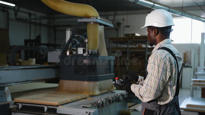 African American Operator Using CNC Machine to Cut Wood Panel stock video