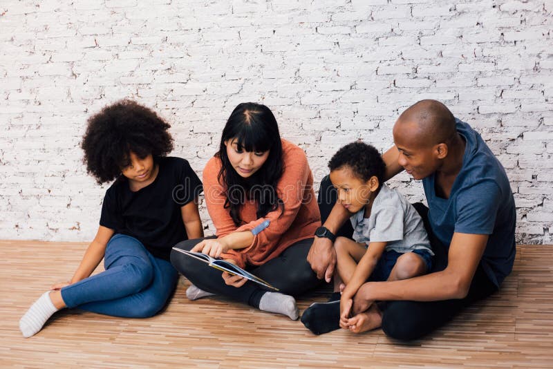 African American parents reading a fairy tale fable story for kids at home. Happy family sitting on the floor indoors. African American parents reading a fairy tale fable story for kids at home. Happy family sitting on the floor indoors