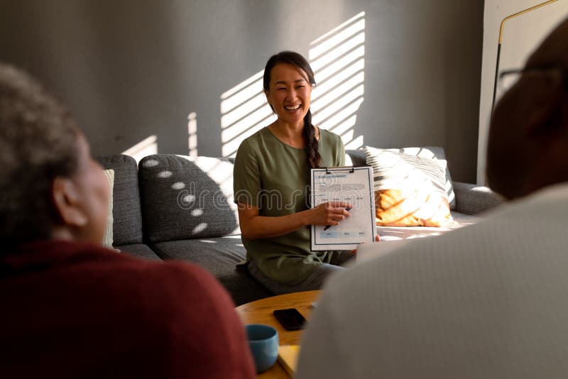 African American Senior Couple Having Meeting With Happy Asian Female Financial Advisor At Home