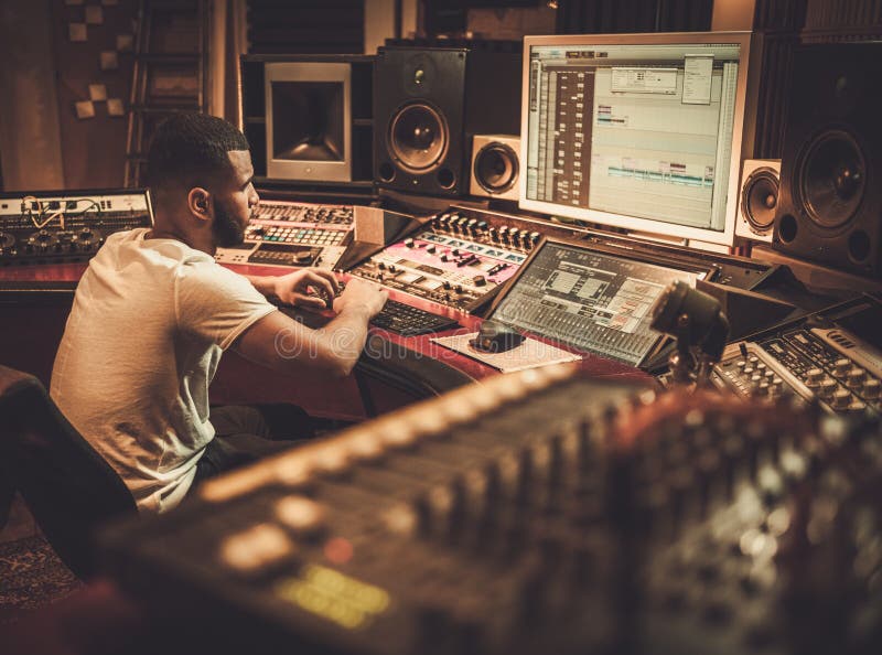 African american sound engineer working at mixing panel in boutique recording studio royalty free stock photography