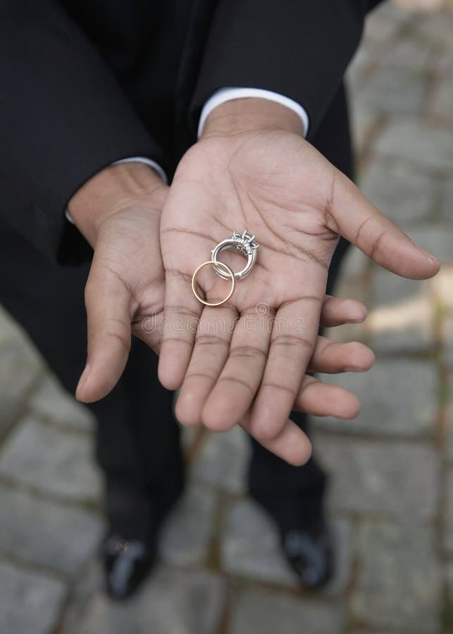 African-American hands holding wedding bands, DOF focus on rings. African-American hands holding wedding bands, DOF focus on rings