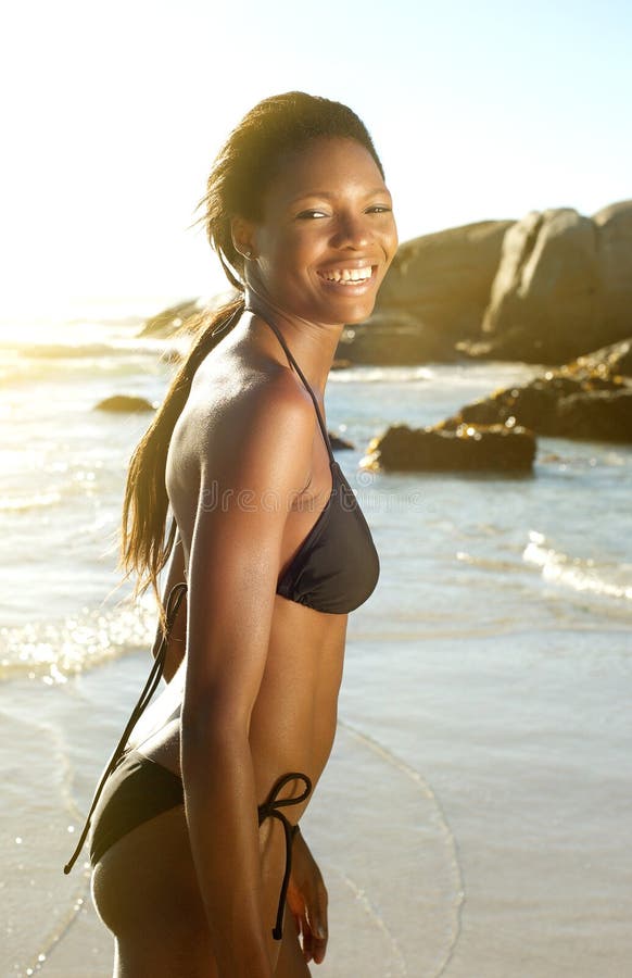 Side view portrait of a beautiful african american woman in bikini smiling at the beach