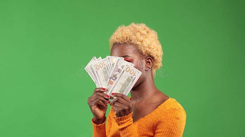 African American woman with a bundle of dollars holding a fan in her hands covers her face