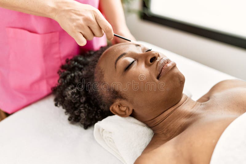 African American Woman Lying On Massage Table Having Eyebrows Treatment At Beauty Salon Stock