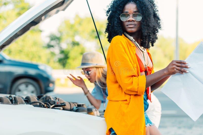 african american woman looking for destination on map while friend checking.