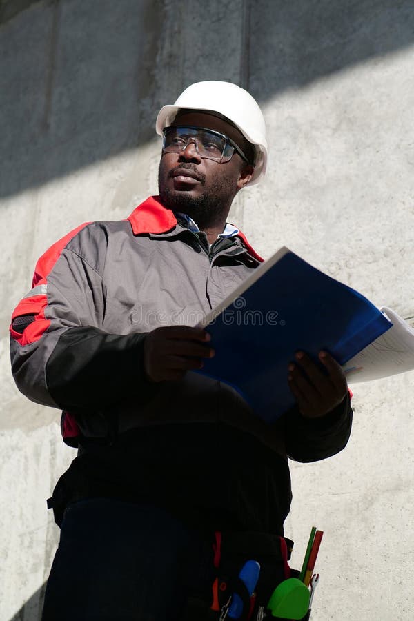 African American Worker Stands at Construction Site with Work Papers