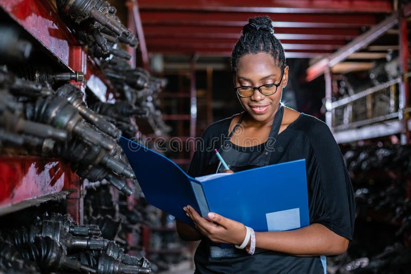 African american worker woman wear spectacles crossed arms holding clipboard standing in factory auto parts.