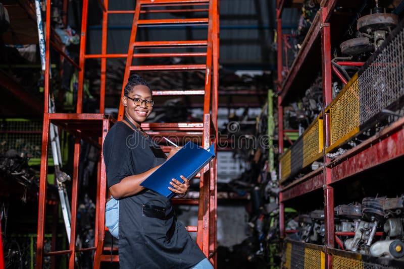 African american worker woman wear spectacles crossed arms holding clipboard standing in factory auto parts.