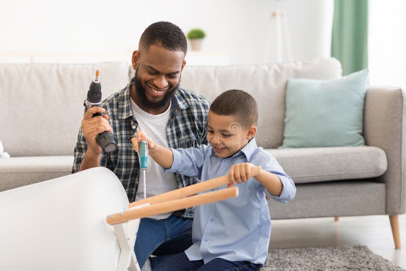 African Boy Helping Father Fix Table Doing Housework At Home