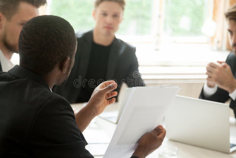 African businessman holding documents talking to partners, close