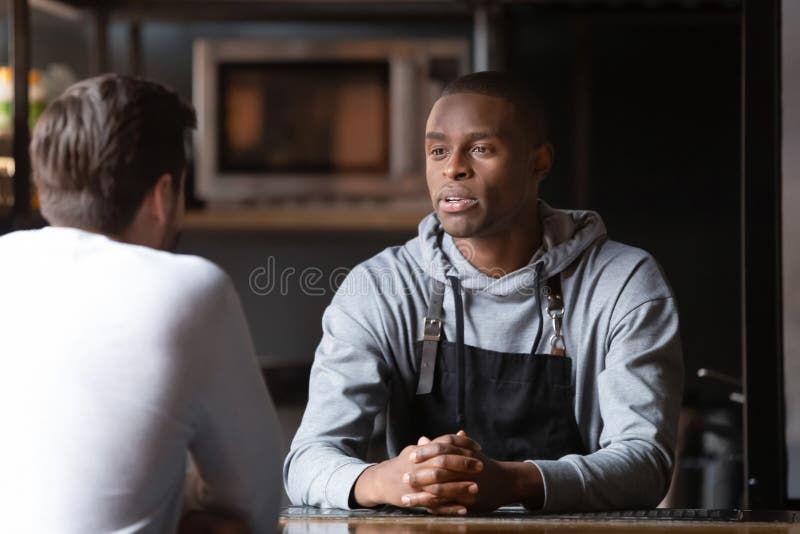 African chef talking with caucasian male vacancy candidate in restaurant stock photography