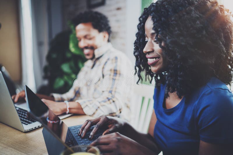 African couple having rest at a home: black girl sitting on sofa,holding touch tablet and laughing,looking through stock photos African couple having rest at a home: black girl sitting on sofa,holding touch tablet and laughing,looking through stock photos