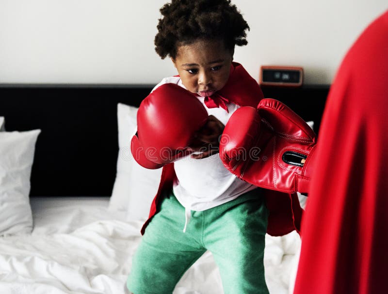 African descent kid wearing robe doing boxing with dad on the be