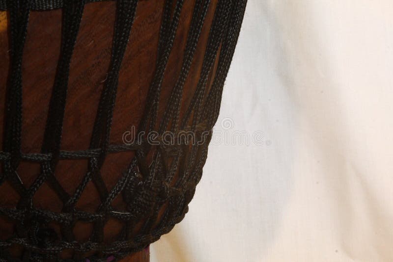 Африканец Джембе Канаты Оставил. Up-close view of a wooden African djembe design with tuning ropes framed on the left side stock image