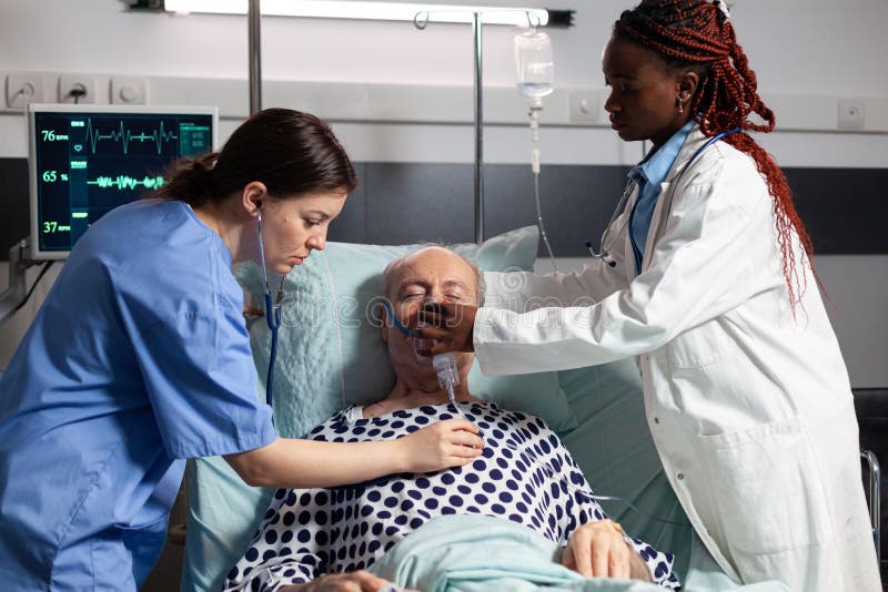 African doctor and medical assistant helping senior man breath