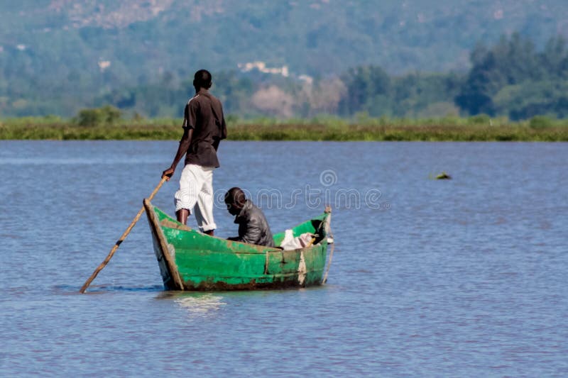 African fisher man on the lake shore in boat preparing the net for fishing. Fisherman working hard in Africa at lake Victoria. African fisher man on the lake shore in boat preparing the net for fishing. Fisherman working hard in Africa at lake Victoria