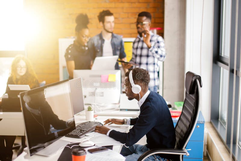African good-looking programmer with headphones working with computer in developing company office. Developing programmer stock images, royalty-free photos and pictures