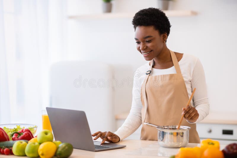 African Lady Cooking Using Laptop Browsing Recipes Online At Home