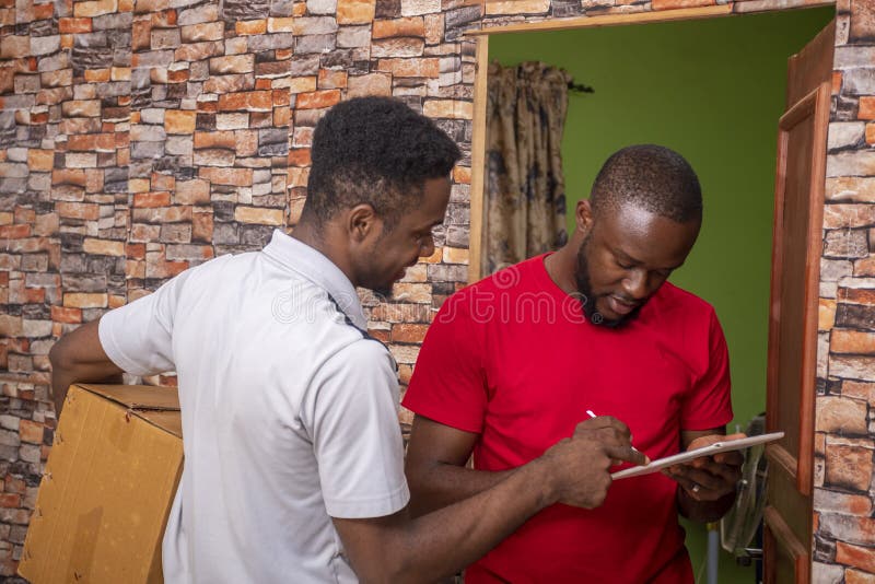 African male signing a proof of delivery while receiving a parcel from the courier