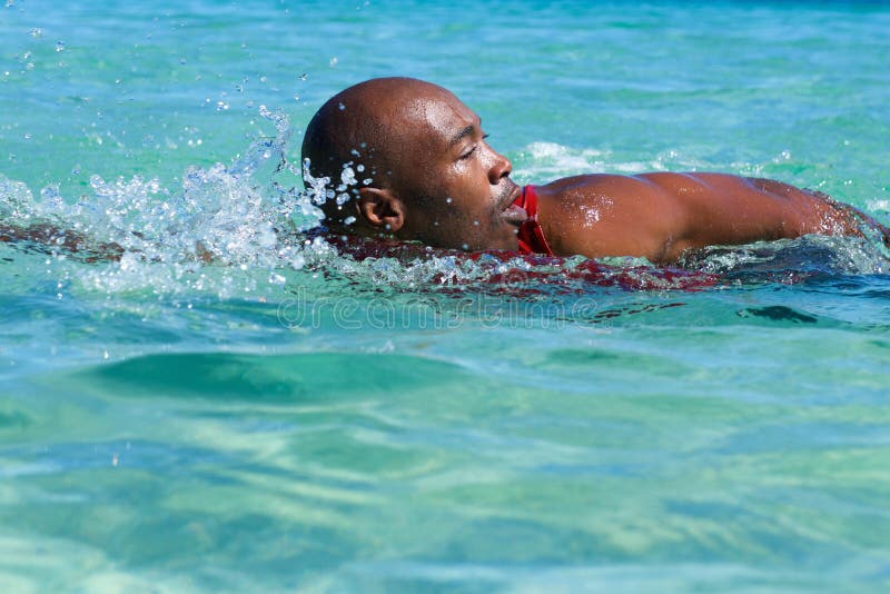 Portrait of fit african male swimmer swimming in sea water