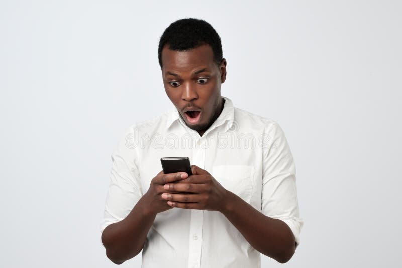 African man looking at phone seeing shocking news or photos with surprised emotion on his face royalty free stock images African man looking at phone seeing shocking news or photos with surprised emotion on his face royalty free stock images