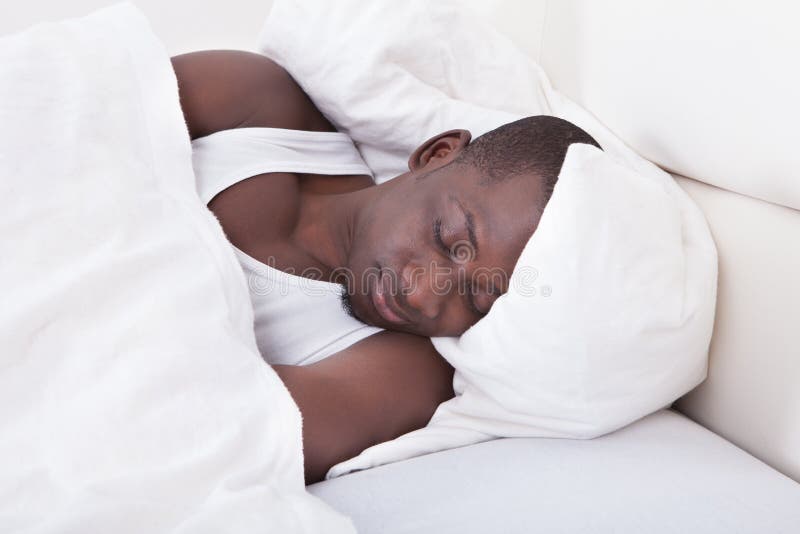 African man sleeping on bed. 