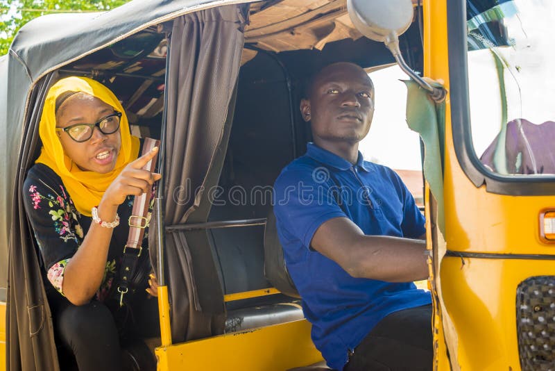 african men driving a auto rickshaw taxi being annoyed by a female passenger who& x27;s talking to him, nigeria, nigerian, young, youth, black, person, guy, tuk, keke, napep, transport, transportation, vehicle, driver, local, lifestyle, smiling, cheerful, town, job, livelihood, lady, woman, muslim, happy, excited, excitement, directions, showing, point, pointing, destination, route, sitting, annoying, angry, irritating, frustrated. african men driving a auto rickshaw taxi being annoyed by a female passenger who& x27;s talking to him, nigeria, nigerian, young, youth, black, person, guy, tuk, keke, napep, transport, transportation, vehicle, driver, local, lifestyle, smiling, cheerful, town, job, livelihood, lady, woman, muslim, happy, excited, excitement, directions, showing, point, pointing, destination, route, sitting, annoying, angry, irritating, frustrated