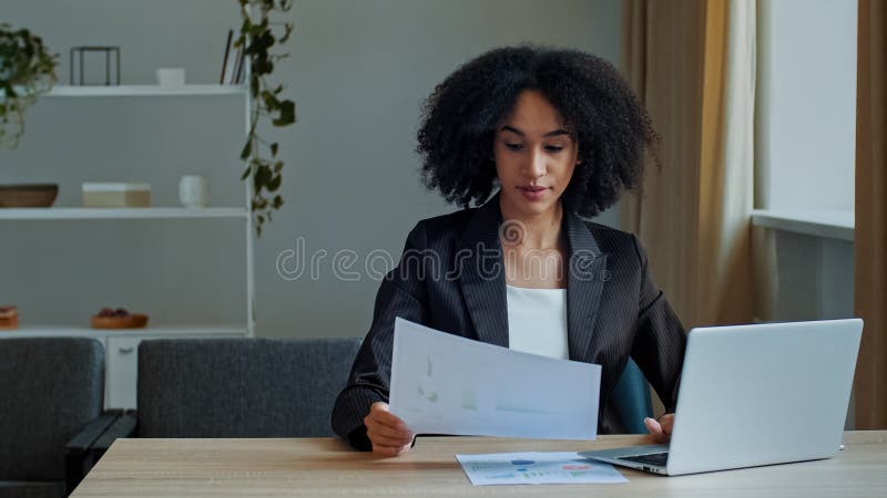 African teacher worker business woman work with graphics documents at home office check documentation enter financial. Data to laptop processing online