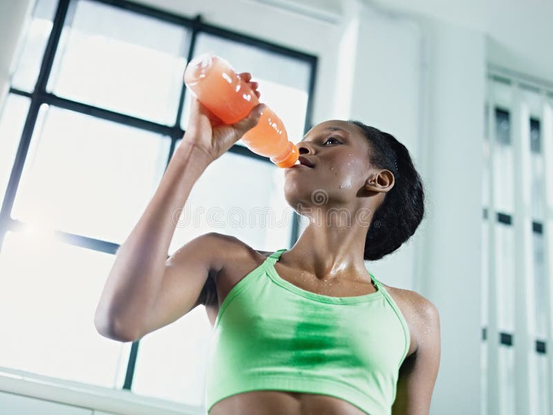 African woman in gym drinking energy drink