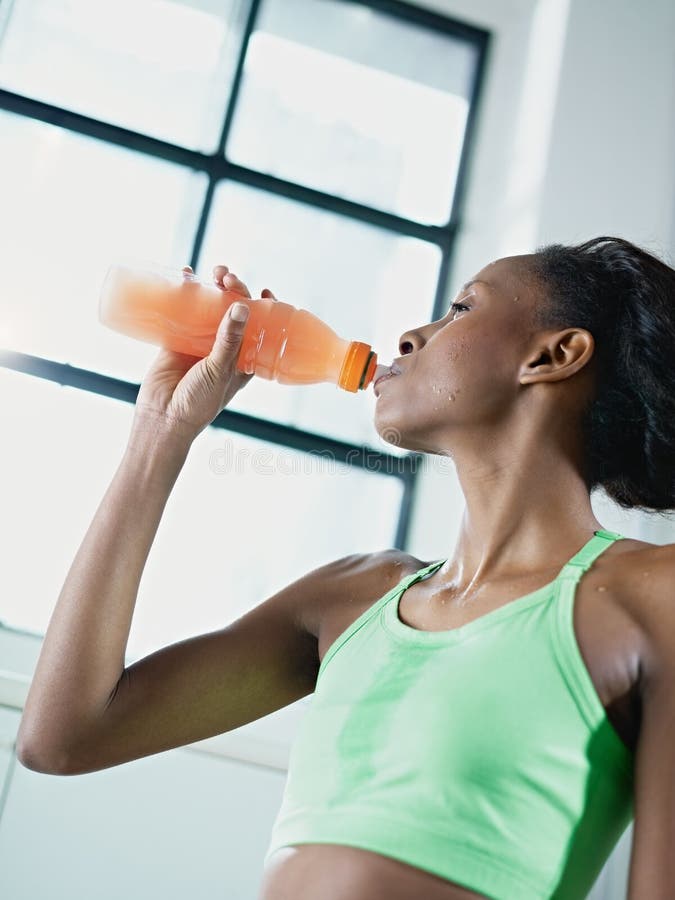 African woman in gym drinking energy drink