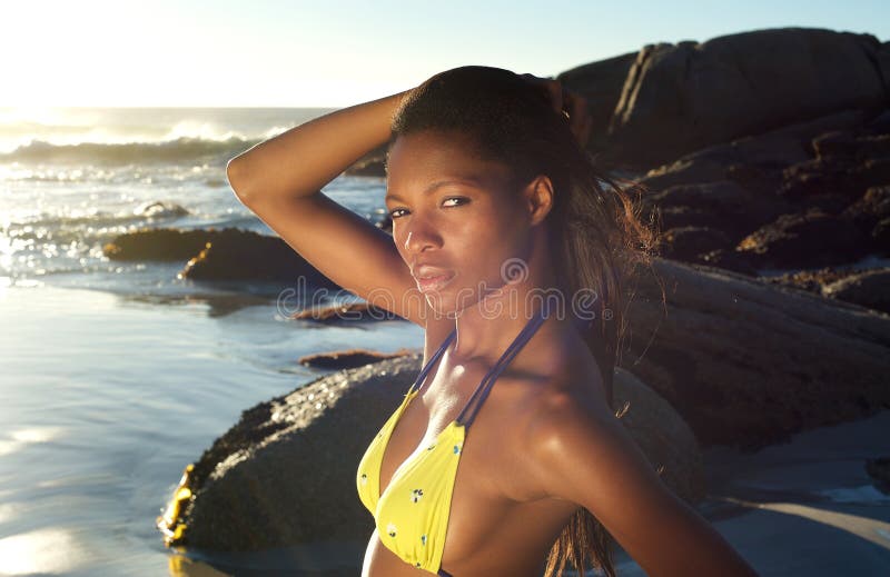 Close up portrait of a beautiful african woman posing with hand in hair at the beach. Close up portrait of a beautiful african woman posing with hand in hair at the beach