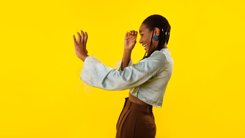 African Woman Pretending Watching Through Invisible Telescope Over Yellow Background stock images