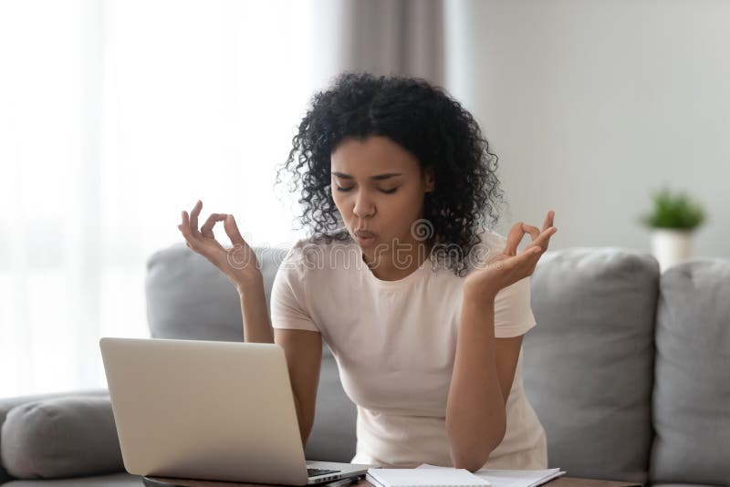 African woman reducing stress do yoga exercise to calm down. African woman sit on couch near laptop take break reduce stress do yoga meditation exercise to calm