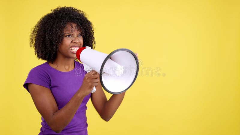 African woman yelling while using a mefaphone in studio with yellow background